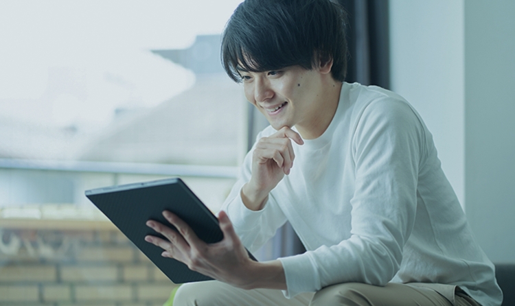 笑顔でタブレット画面を見つめる男性の写真